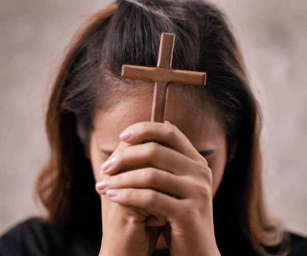 A young Asian Christian woman praying to Jesus Christ in a church.